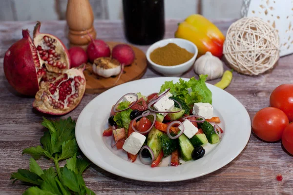 Greek salad on a white plate. Good nutrition. National cuisine. Salad with cucumbers, tomatoes, feta cheese, olives and herbs