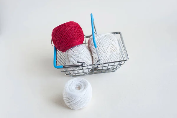 shopping basket with white and red threads on a light background