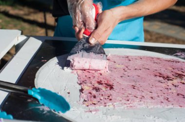 Şef pembe bir dondurma rulosu yapıyor. Sokak şekerleri