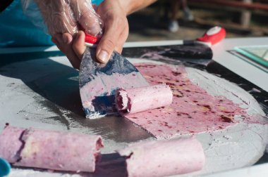 Şef pembe bir dondurma rulosu yapıyor. Sokak şekerleri