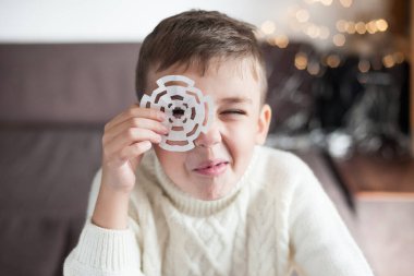 Elinde kar tanesi olan beyaz kazaklı bir çocuk. Kutlama için hazırlık. Yeni yıl için dekorasyon