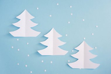 Mavi arka planda kağıttan yapılmış üç Noel ağacı. Noel kartı.