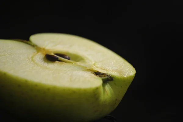 Slyced half green apple on black background