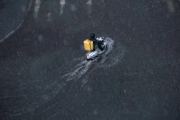Motorrijder Rijdt Een Overstroomde Straat Met Een Gele Rugzak Zijn Stockfoto