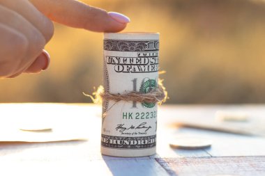 Güzel gün batımı arka planında ip ile sarılmış yüz dolarlık banknot. Finansal tasarruf ve büyüme kavramı.