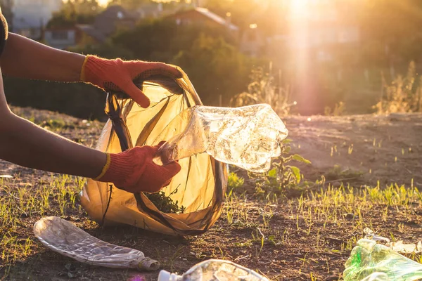 Garbage bottles picked up and thown into a trash bag. Plastic and food waste concept. Clean planet Earth, collect garbage, avoid pollution, save environment.