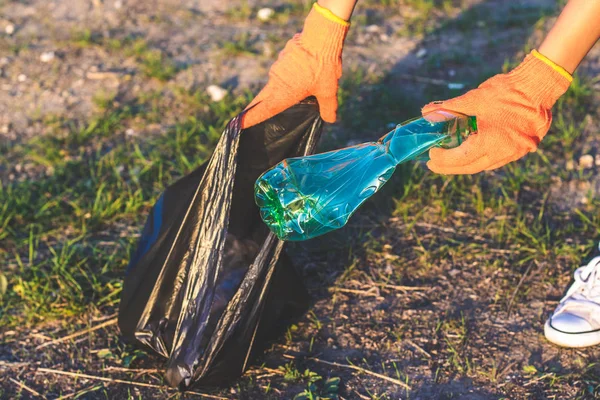 Garbage bottles picked up and thown into a trash bag. Plastic and food waste concept. Clean planet Earth, collect garbage, avoid pollution, save environment.