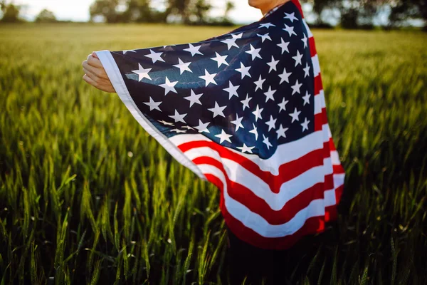 新しい収穫の間に若い愛国的な農家の閉鎖が立っている 独立記念日を祝う緑の小麦畑でアメリカ国旗を手に歩く少年 7月4日のコンセプト — ストック写真
