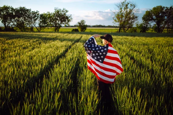 셔츠와 모자를 남자가 녹색밀 밭에서 국기에 있습니다 애국심 소년은 국기를 — 스톡 사진