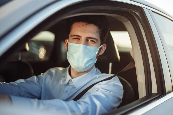 Genç taksi şoförü, steril tıbbi maske takarak yolcuyu gezdiriyor. Direksiyonun başındaki arabada Coronavirus salgınında çalışan bir adam var. Sosyal uzaklık ve sağlık güvenliği kavramı