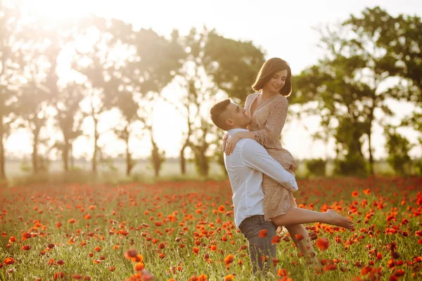 一对浪漫的夫妇在夕阳西下的罂粟田里玩得很开心 一个男孩双手牵着一个女孩 在红罂粟花丛中感到快乐 家庭价值观 团结观念 — 图库照片