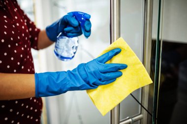 Coronavirus pandemik karantinası sırasında ofiste, üzerinde dezenfektan ve temizlik kapısı kolu olan mavi lastik eldivenler giyen kadınların fotoğrafları. Sağlık hizmetleri, adaptasyon kavramı