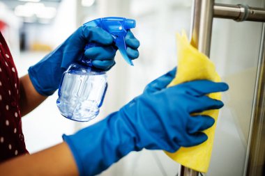 Coronavirus pandemik karantinası sırasında ofiste, üzerinde dezenfektan ve temizlik kapısı kolu olan mavi lastik eldivenler giyen kadınların fotoğrafları. Sağlık hizmetleri, adaptasyon kavramı