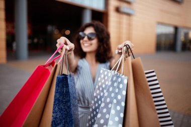 Alışveriş merkezinden alışveriş meraklısı genç bir kadın bir paket alışveriş çantasıyla çıkıyor. Saplantılı bir kızın elinde pembe alışverişçi. Alışveriş, giysi ve para harcama kavramı