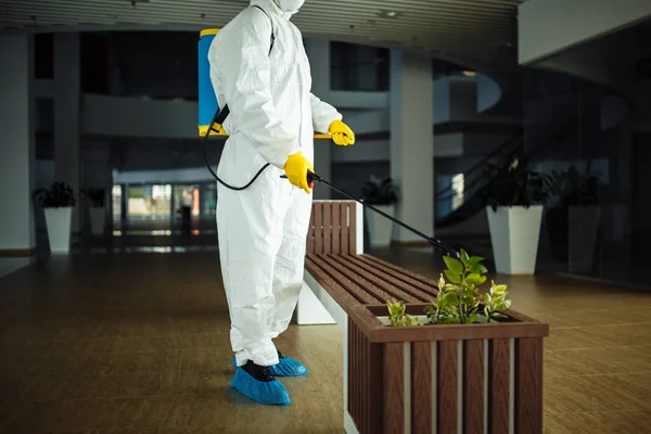 Hombre Con Traje Protector Está Desinfectando Banco Centro Comercial Vacío —  Fotos de Stock