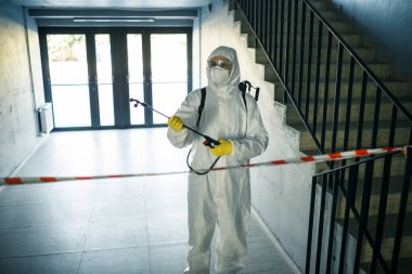Alışveriş merkezindeki merdivenleri antiseptikle temizleyen işçi kovid 19 yayılmasını önlemek için. Dezenfekte kıyafeti giymiş bir adam merdivenleri spreyliyor. Sağlık, karantina ve hijyen kavramı