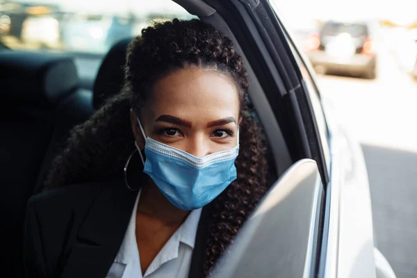 Young businesswoman took a taxi and having a ride as a passenger during covid-19 pandemic quarantine. Business trips during pandemic, new normal and coronavirus travel safety concept