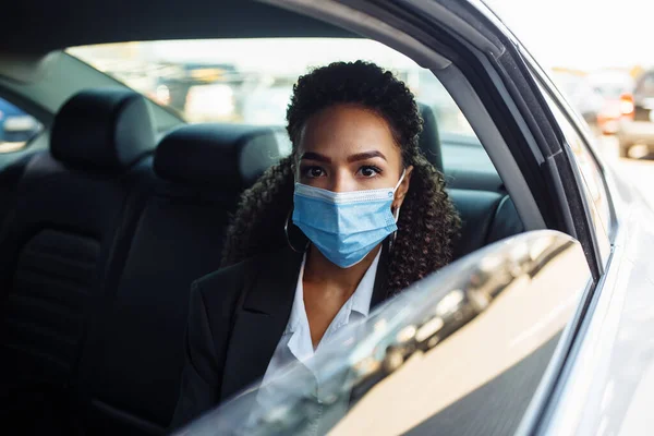 Young businesswoman took a taxi and having a ride as a passenger during covid-19 pandemic quarantine. Business trips during pandemic, new normal and coronavirus travel safety concept