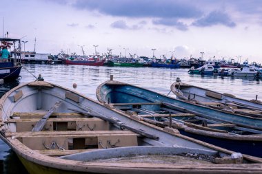Limanda demirli üç balıkçı teknesi var. Arka planda liman olan mavi gökyüzü günbatımı
