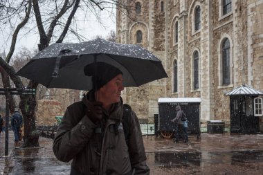 Londra Kulesi 'nde kar altında siyah şemsiyeli yetişkin bir adam..