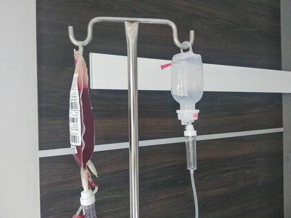 病院の白い壁の背景の輸血は血滴を示しています — ストック写真