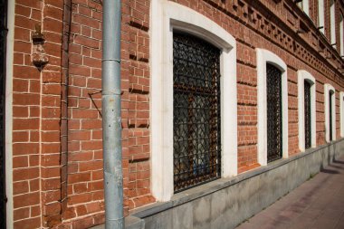 Üzerinde parmaklık ve beyaz çerçeve olan bir dizi pencereli tuğla duvar..