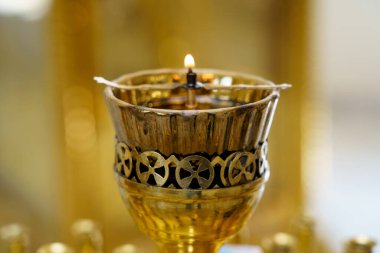 A single candle illuminates an ornate lamp decorated with intricate designs. This scene takes place during a spiritual ceremony, highlighting the reverence of the moment in a sacred space filled with warmth and light.