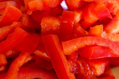 Bright and vibrant diced red bell peppers are arranged on a surface, showcasing their fresh and crunchy texture. Perfect for enhancing salads or stir-fries, these peppers bring color and taste to various dishes.