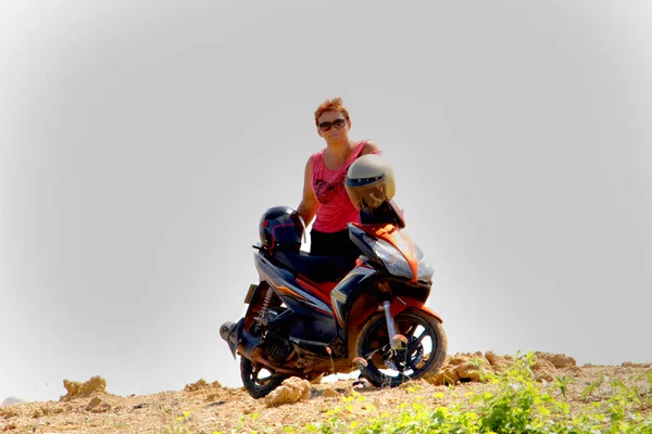 Silhouet van een vrouw paardrijden een scooter, lucht achtergrond — Stockfoto