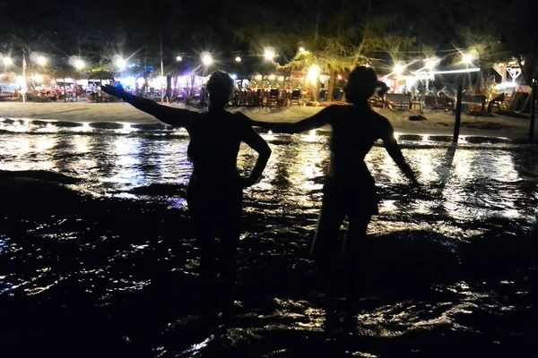 Silhuetter av två kvinnor som simmar på natten i havet 2 — Stockfoto