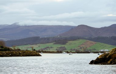 Arka planda Kantabriya sıradağları bulunan San Vicente de la Barquera limanına giriş
