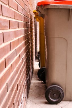 Tuğla duvara yakın bazı çöp kutuları
