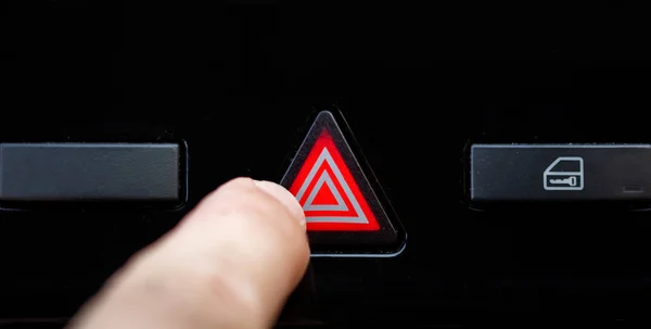 Hand ready to press the warning button of a car, Button on