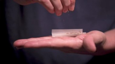 Sigara kağıdına tütün döken bir elin yavaş hareketi.