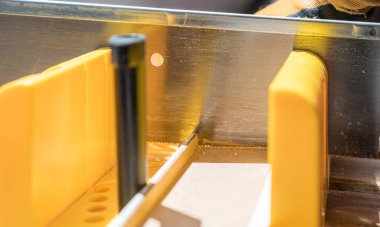 Eldivenli ve el testereli bir adamın, elektrikli testereyle ahşap bir şerit keserken makro fotoğrafı.