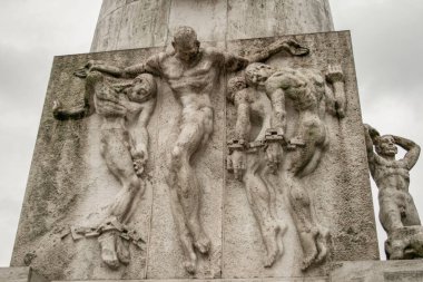 Amsterdam, Hollanda, 01 / 21 / 2008: Amsterdam Ulusal Anıtı 'nın ayrıntıları, büyük dikilitaşın altında dört adet zincirlenmiş adam ve çıplak adam figürü bulunuyor
