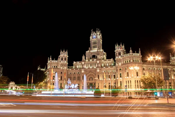 Madrid, İspanya; 08 / 05 / 2020: Fuente de Cibeles ve Madrid İl Meclisi 'nin yanındaki araçların trafiğinin çizdiği ışık çizgilerinin gece fotoğrafları