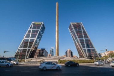 Madrid, İspanya; 10 / 08 / 2016: Arka planda mavi gökyüzü bulunan Obelisco de la Caja ve Plaza de Castilla 'nın yanındaki Puerta de Europa, Torres Kio ve Cuatro Torres İş Alanı