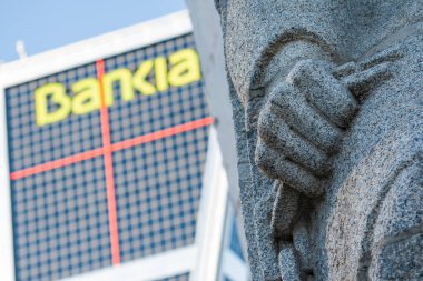 Madrid, İspanya; 10 / 08 / 2016: Bankia (İspanyol Bankası) sözcüğünün ön plandaki bir heykelin tek eliyle Kio kulelerinin cephelerinden birine odaklanmaması