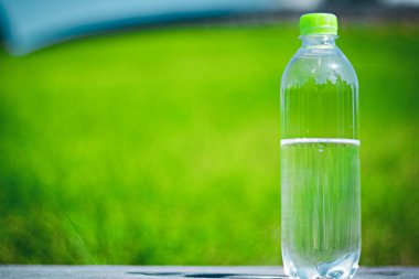 Bulanık arka plan bir yeşil üzerinde sıvı su ile Plastik şişe