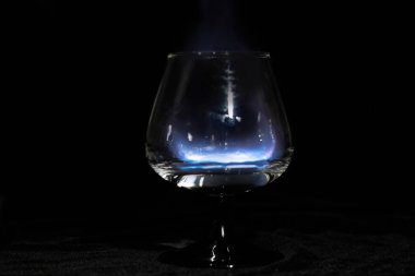 Siyah bir arka plan üzerinde yanan bir sambuca ile Konyak cam
