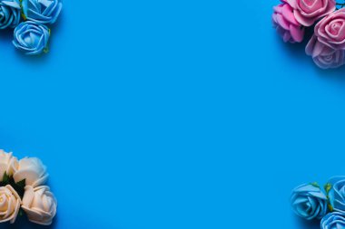 metin için mavi bir arka plan çerçevesi üzerinde yapay güller. kopyalama alanı