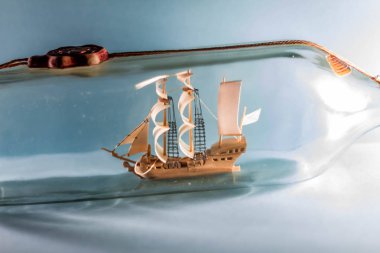 Mavi arka planda bir şişe içinde gemi