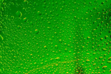 Pencere camlarında yağmur damlaları var. Mavi arka planda yeşil renkli doğal yağmur damlaları..