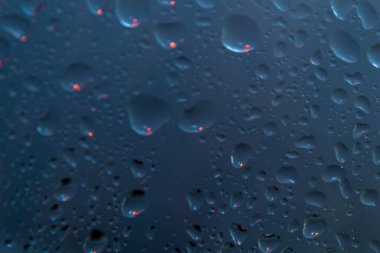 Pencere camlarındaki yağmur damlaları mavi arkaplandaki doğal yağmur damlaları..