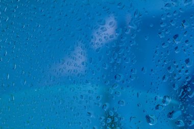 Pencere camlarındaki yağmur damlaları mavi arkaplandaki doğal yağmur damlaları..