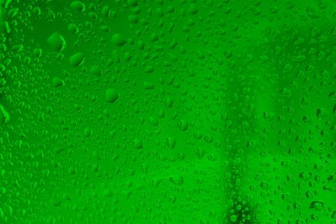 Pencere camlarında yağmur damlaları var. Mavi arka planda yeşil renkli doğal yağmur damlaları..