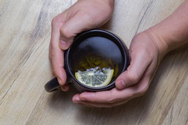 Siyah bir fincanda limonlu yeşil çay. Tahta bir parkede.