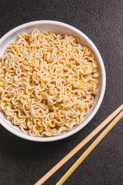 Fideos de primer plano en un plato con palillos de bambú en una mesa negra ley plana — Foto de Stock