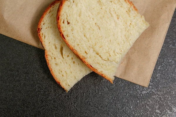 Δύο φέτες ψωμί σε ψωμί χαρτί σε μαύρο τραπέζι αντίγραφα χώρο επίπεδη lay — Φωτογραφία Αρχείου